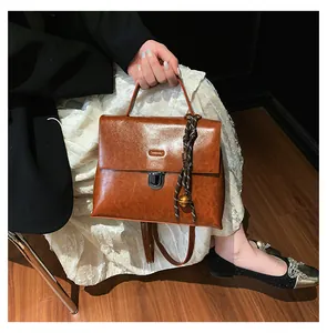 Detail der braunen Vintage-Handtasche mit Metallschnalle und gewebtem Glockenanhänger