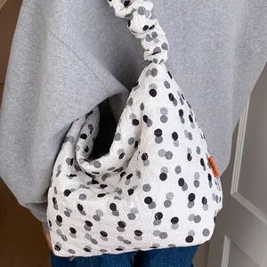 Quilted white shoulder bag with black polka dots and wavy cloud-shaped pleated strap