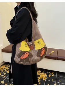 Close-up of a brown knitted tote bag featuring cute cartoon bear embroidery with yellow hat