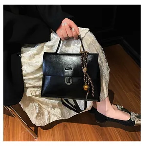 Details einer schwarzen Vintage-Lederhandtasche mit silberner U-Schnalle und Anhänger