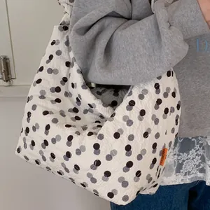 Quilted oversized white tote bag with black polka dots and orange brand label