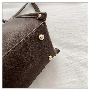 Detailed macro view of dark brown leather bag with golden rivets and precise stitching