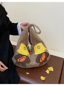 Detailed close-up of brown striped knit tote bag with cute cartoon bear embroidery