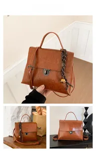 Details einer braunen Vintage-Handtasche aus Leder mit Metallschloss und Glocken-Anhänger
