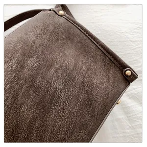 Macro detail of dark brown cracked leather bag with gold rivet accents and texture