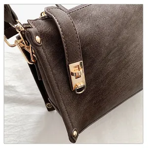 Detailed macro view of dark brown leather square bag with gold hardware and twist-lock clasp