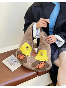 Detailed view of brown knit tote bag with cute bear embroidery and wooden buckle closure