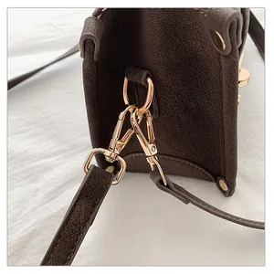 Detail of dark brown vintage faux leather bag showing gold hardware and D-ring attachments