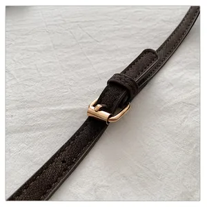 Close-up of dark brown leather strap with polished gold buckle and fine stitching