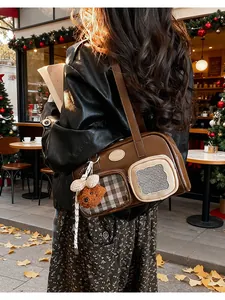 Détail d'un sac en cuir marron avec charme d'ours dans un café d'hiver chaleureux