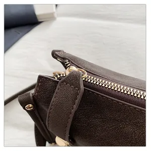 Close-up of premium brown lychee textured leather with gold metal zipper and stitching