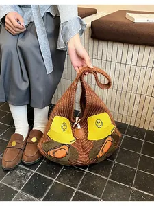 Detail of a brown knitted tote bag with cartoon puppy patches and a wooden button closure
