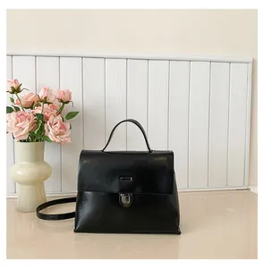 Detailaufnahme einer schwarzen Vintage-Umhängetasche aus Leder mit Metallschnalle auf Weiß