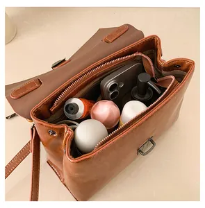 Detailansicht der braunen Ledertasche mit geräumigem Innenfach und Alltagsgegenständen