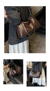Détail du sac Boston en cuir marron foncé avec une finition brillante et bandoulière