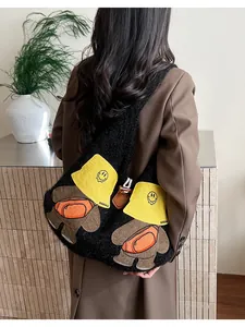 Close-up of black fleece tote bag featuring cute cartoon bear embroidery and yellow hat