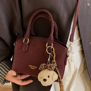 Retro burgundy frosted leather handbag with leopard plush pendant on dark coat
