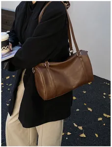 Détail d'un sac Boston cylindrique marron en similicuir lisse avec ferrures argentées