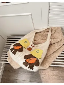 Detail of white knit tote bag with 3D bear embroidery and wooden toggle closure