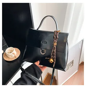Nahaufnahme der schwarzen Retro-Tasche mit silbernem Drehverschluss und Goldanhänger