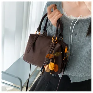 Detail of dark brown leather Boston bag featuring colorful charms and vintage hardware