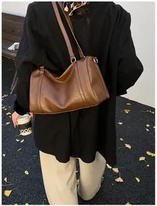 Gros plan d'un sac Boston vintage en cuir marron avec doubles anses et logo embossé