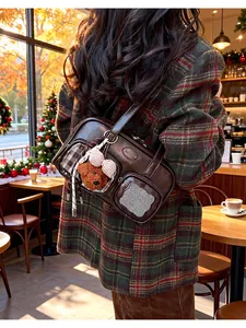 Détail du sac en cuir marron foncé avec poches avant et un joli porte-clés en ours peluche