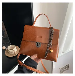 Details der braunen Vintage-Tasche aus Öl-Wachs-Leder mit Metallschloss und Glockenanhänger