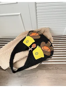 Detail of plush black tote bag with cute bear paw appliques and yellow knit hat accents