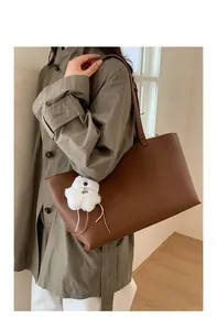 Close-up of brown PU leather tote bag texture with a cute white plush puppy charm