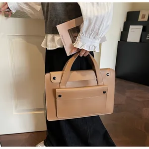 Detail of light brown leather tote bag with front pocket flap and black snap buttons