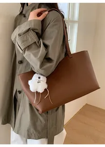 Brown faux leather tote bag with lychee texture and plush bear charm on female model
