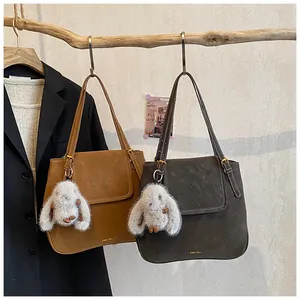 Detail view of suede bucket tote bags in brown and grey with plush bunny charms