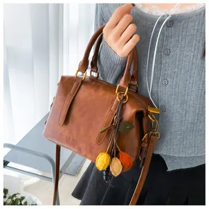 Detail view of a vintage reddish-brown Boston bag with golden hardware and fruit charm