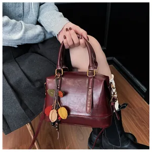 Detail of burgundy Boston pillow bag with oil-wax leather texture and colorful leaf charms