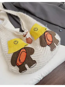 Close-up of white knit tote bag featuring bear embroidery and wooden toggle button closure