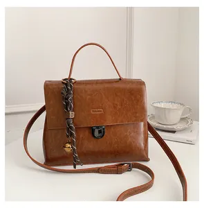 Details der braunen Vintage-Tasche mit Metallverschluss, Streifenband und Goldkugel-Anhänger