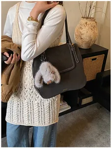Detail of dark brown bucket bag featuring contrast white stitching and plush rabbit charm