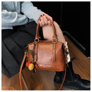 Close-up of a brown vintage leather Boston bag with a unique fruit charm detail