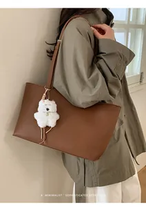 Detail of dark brown PU tote bag with a soft plush puppy charm and slim straps