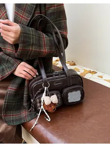 Détail du sac polochon en similicuir marron foncé avec poches et charm ours en peluche