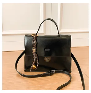 Detailansicht der schwarzen Ledertasche mit goldener Perle und Metall-Drehverschluss