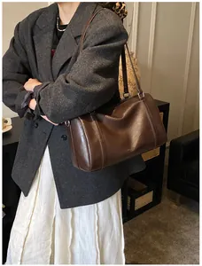 Détails de la texture du cuir PU marron foncé et boucle métallique sur le sac Boston