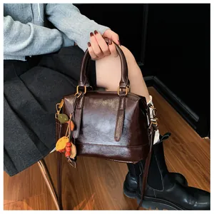 Detailed macro of dark brown glossy Boston bag with vintage leaf charms and gold hardware