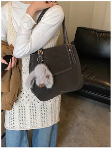 Detail of dark brown leather tote bag with white contrast stitching and bunny pendant