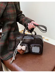 Détail du sac polochon marron brillant avec mini poches et breloque ours en peluche