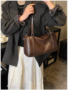 Détail du sac cylindre en cuir marron foncé avec fermeture éclair et fines poignées