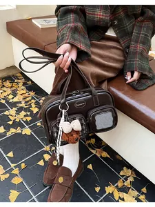 Gros plan du sac oreiller en PU marron foncé avec plusieurs poches et pendentif ours en peluche