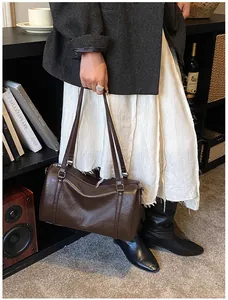 Détail d'un sac Boston rétro en cuir marron foncé avec de longues bretelles élégantes