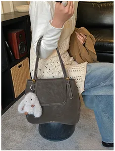 Detail of dark brown bucket bag featuring contrast white stitching and plush bunny charm